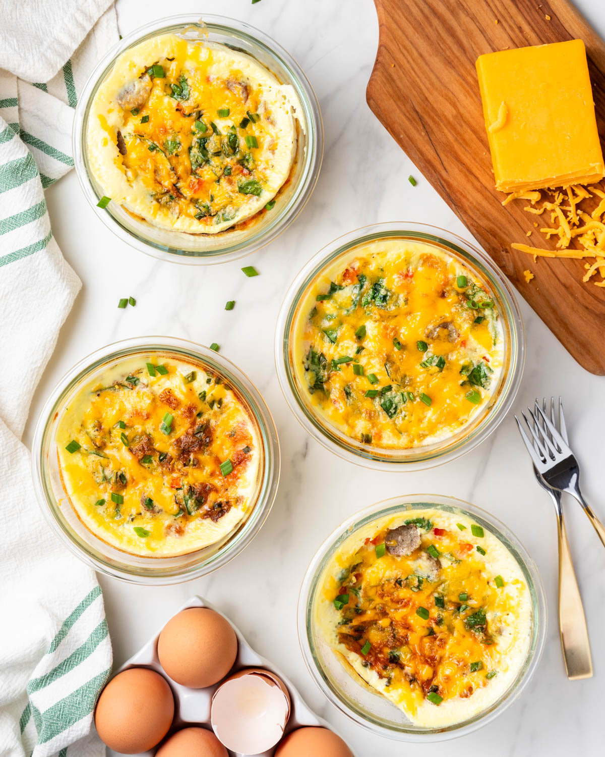 Individual baked egg cups with sausage, vegetables, and melted cheese